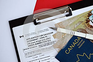 Application for Canadian citizenship for adults on table with pen, passport and dollar bills