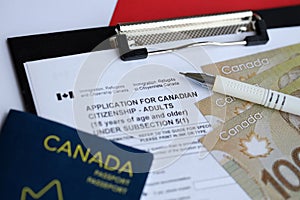 Application for Canadian citizenship for adults on table with pen, passport and dollar bills