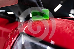 Application of a colorless protective film at a car detailing studio or car wash.