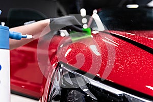 Application of a colorless protective film at a car detailing studio or car wash.