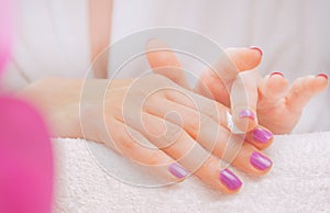 Application of cream on female hands with purple nail