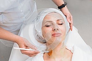 Application of an enzyme mask with a brush on a woman`s face top view