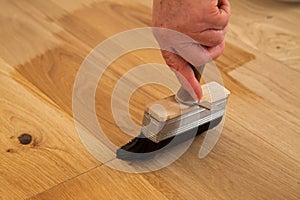 Application of oil-based floor finish on luxury oak parquet flooring, which tends to enhance the appearance of parquet