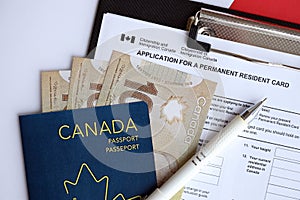 Application for permanent resident card on table with pen and canadian passport with money
