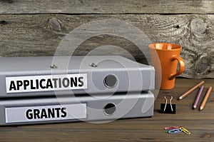 Applications and Grants - two folders on wooden office desk