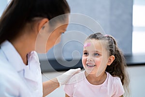 Applying Band Aid To Children Wound