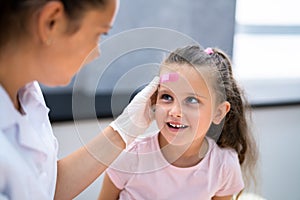 Applying Band Aid To Children Wound