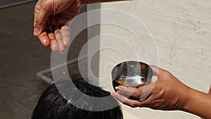 Applying coconut oil mixed with fenugreek seeds and curry leaves to head to nourish the hair, health care concept