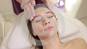 Applying cream to a woman's face with massaging movements by a beautician, carboxytherapy procedure.