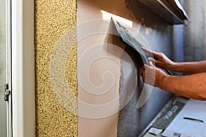 Applying decorative mosaic plaster on the wall.