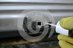 Applying epoxy primer with a brush to part being repaired of damaged galvanized car body photo