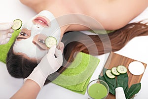 Applying facial mask at woman face on a white background