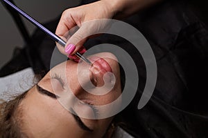 Applying foundation on the lip contour before the permanent makeup procedure. Delicate permanent lip makeup for blondes