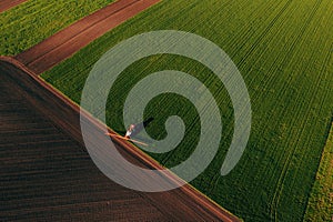 Applying fungicide chemicals on wheat seedling field, aerial view of tractor with crop sprayer