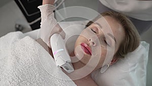 Applying gel on the face in a beauty salon. Application of cosmetic procedures using a laser device. Facial treatment of