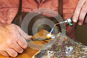 Applying heat - Jewelry manufacturing. Cropped view of a manufacturing jeweler at work with a small acetylene torch.