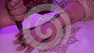 Applying a henna tattoo with a needle on a woman`s hand. Closeup shot. Morocco...Arab wedding. Moroccan traditions.