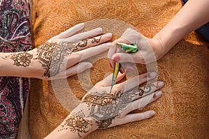 Applying henna tattoo on women hands