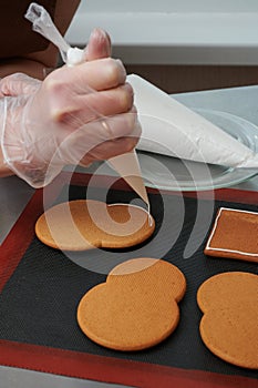 applying a layer of glaze to a confectionery product using a pastry bag. A row of gingerbread cookies on the kitchen