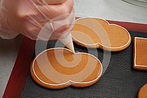 applying a layer of glaze to a confectionery product using a pastry bag. A row of gingerbread cookies on the kitchen