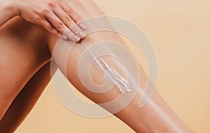 Applying moisturizer cream on legs. Cellulite or anti cellulite treatment. Cosmetic cream on woman leg with clean soft