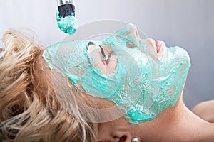 Applying mud face pack on woman face