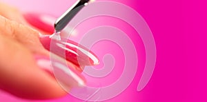 Applying Nail polish, pink shellac UV gel, varnish, manicure process concept in beauty salon.