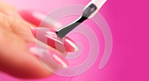 Applying Nail polish, pink shellac UV gel, varnish, nails manicure process concept in beauty salon