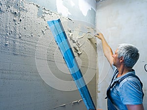 Applying plaster putty to the wall using a aluminum paver screed.