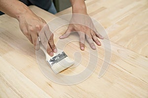 Applying protective painting varnish by hand on a wooden texture, diy and repair house equipment concept