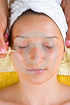 Applying serum to woman eyes skin