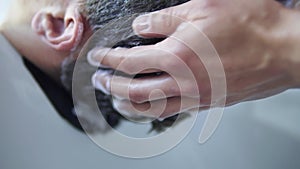 Applying shampoo to male head inside the sink at hairdresser salon