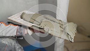 Applying thinset mortar on a tile. Apply the adhesive, closeup. A worker applies tile adhesive to a tile.