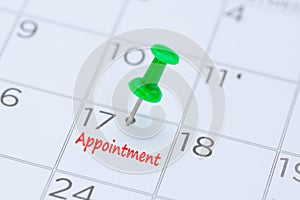 Appointment written on a calendar with a green push pin to remind you and important appointment.