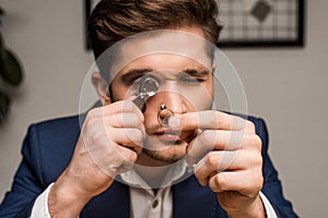 Appraiser with magnifying glass examining jewelry photo