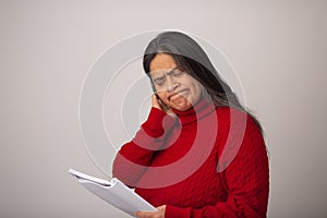 Apprehensive Hispanic Woman Looks Through Notes photo