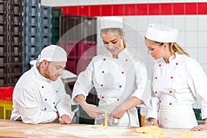 Apprentice in bakery trying to make pretzels and sceptical bakers watching