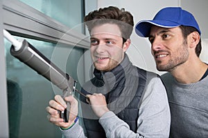 Apprentice being advised how to apply caulk to window