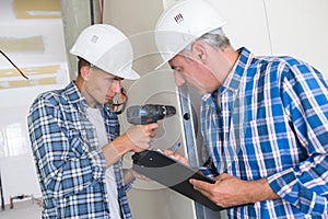 Apprentice construction worker drilling wall