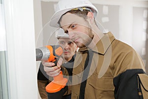 Apprentice construction worker drilling wall