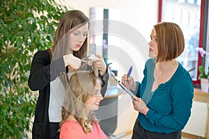 Apprentice cutting hair while instructor is watching