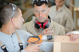 apprentice drilling hole in wooden board