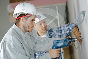 apprentice drilling holes at construction site