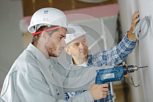 Apprentice drilling holes at construction site