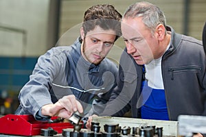Apprentice engineer measuring component with micrometer