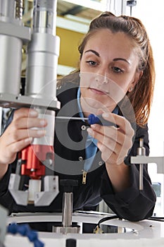 Apprentice Female Engineer Working On Machine In Factory