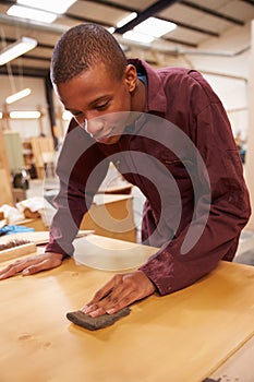 Apprentice Finishing Wood In Carpentry Workshop