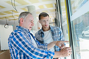 Apprentice glazier with instructor installing window at site