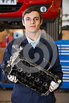 Apprentice Machanic Holding Engine Block In Garage