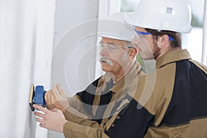 Apprentice male builder sanding wall indoors
